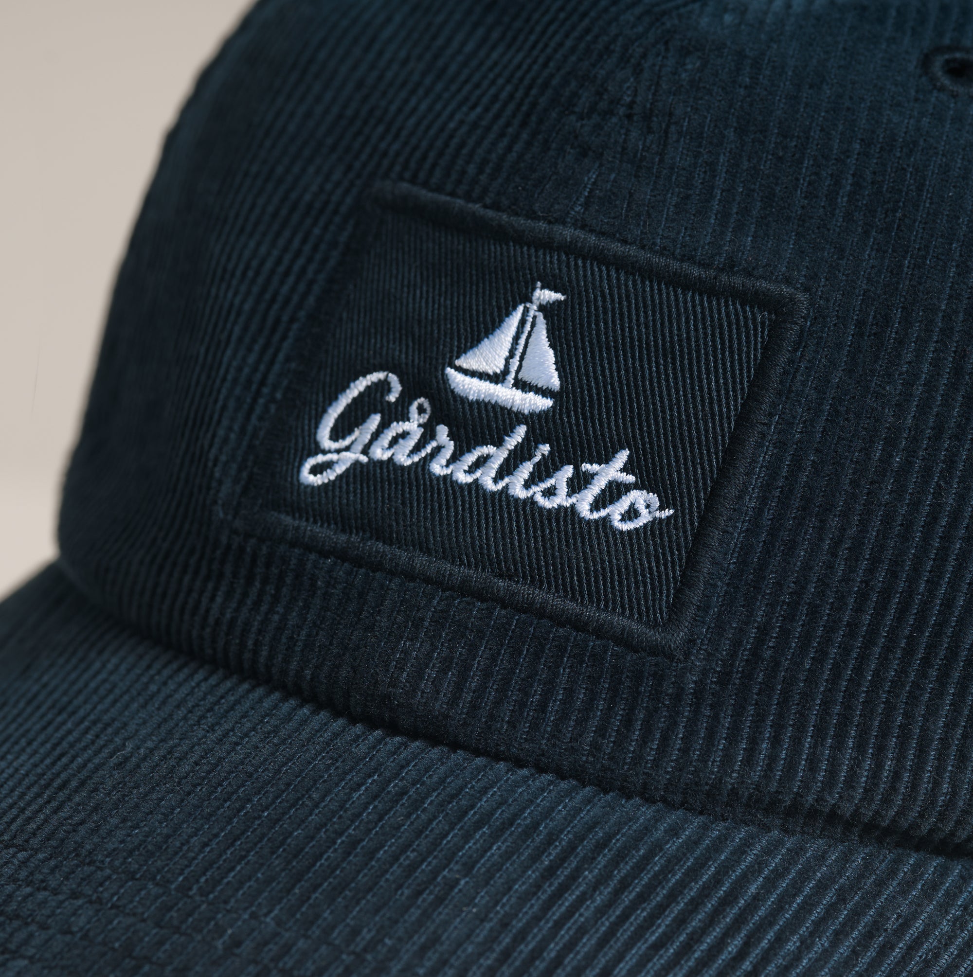 Embroidered Gårdisto sailboat logo on navy corduroy cap